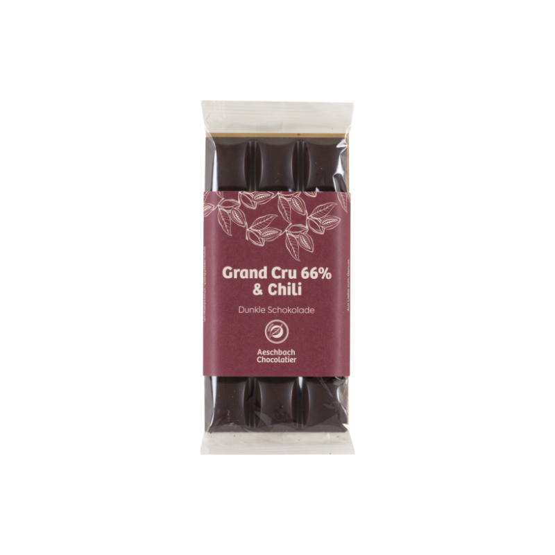Dunkle Schokolade Grand Cru 66% mit Chiliflocken von Aeschbach Chocolatier, zeigt Stücke dunkler Schokolade mit Chiliflocken.